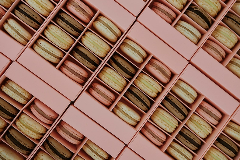 Macarons in verschiedenen Farben, verpackt in rosafarbenen Schachteln
