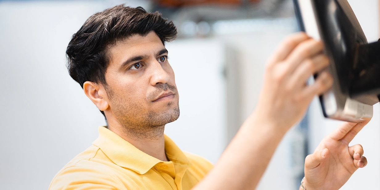 Ebiram Ahmad trägt ein gelbes Polo und blickt auf einen Bildschirm.