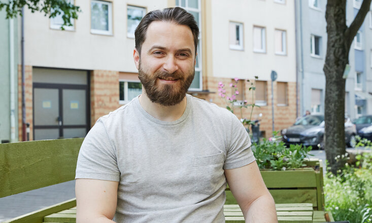 Sorin-Vasile Cioabanu sitzt auf einer Bank vor einer Häuserwand.
